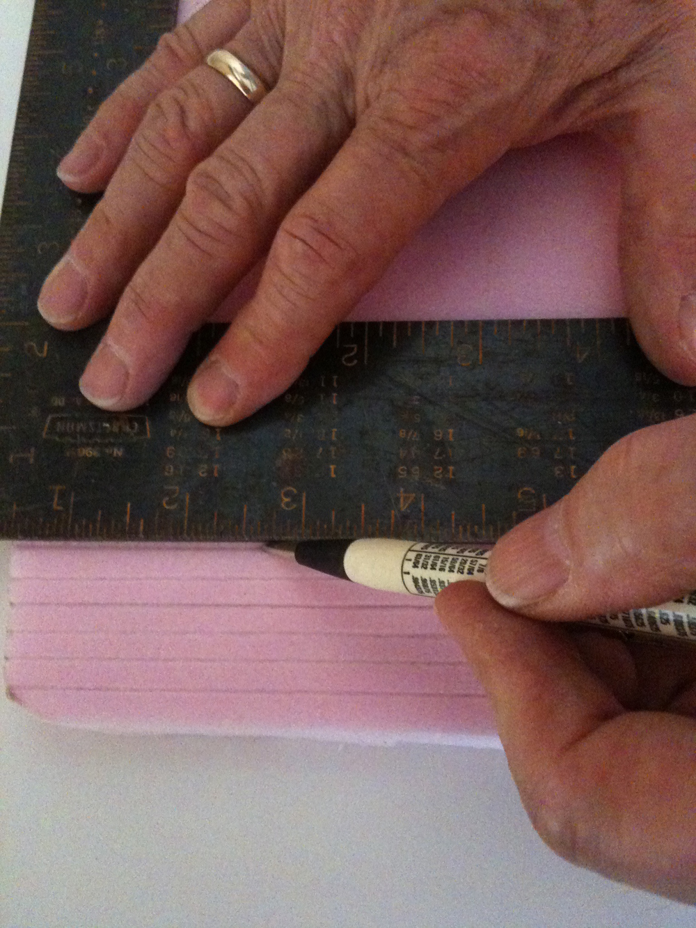 Hands scribing lines into pink insulation foam