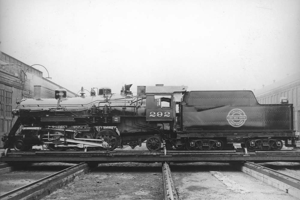 Steam locomotive stands on transfer table between buildings