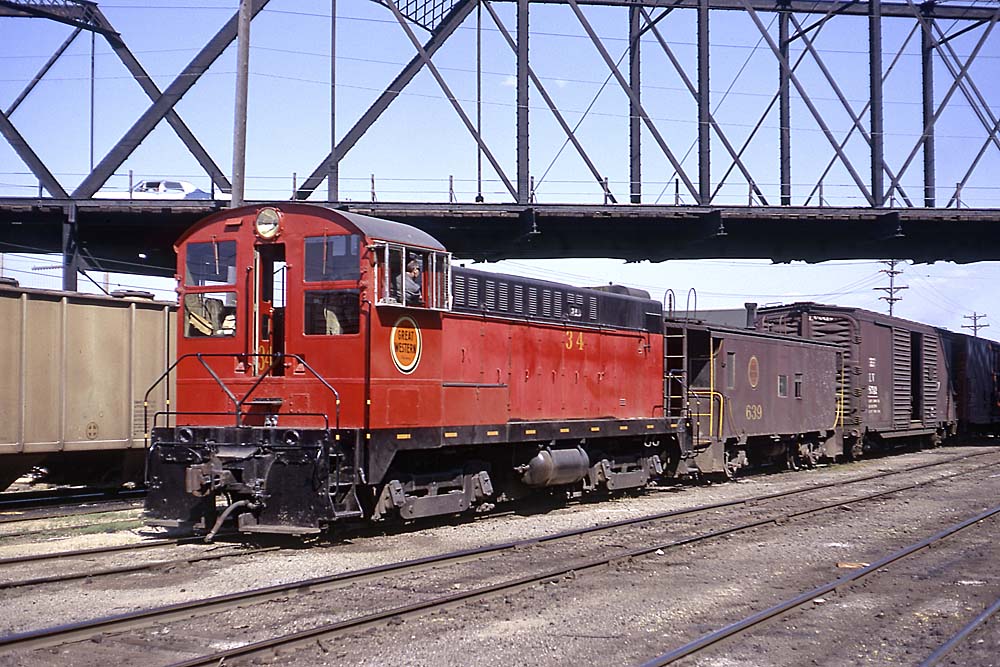 Red and black diesel locomotive with caboose and train under bridge