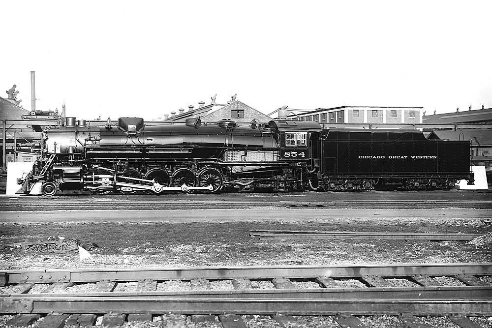 Profile of steam locomotive in front of factory