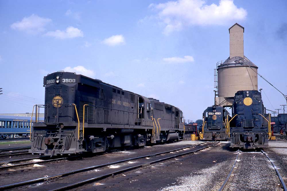 Blue diesel locomotives stand in front of concrete coaling tower