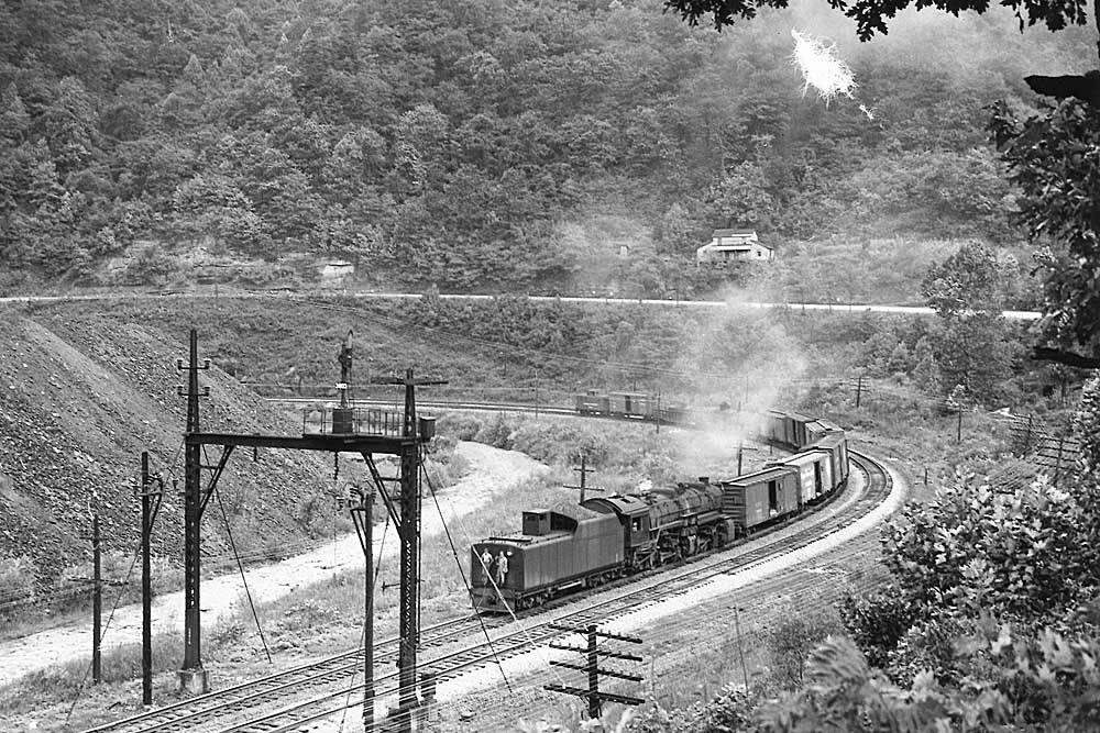 Steam locomotive reverses with short train on curve in valley