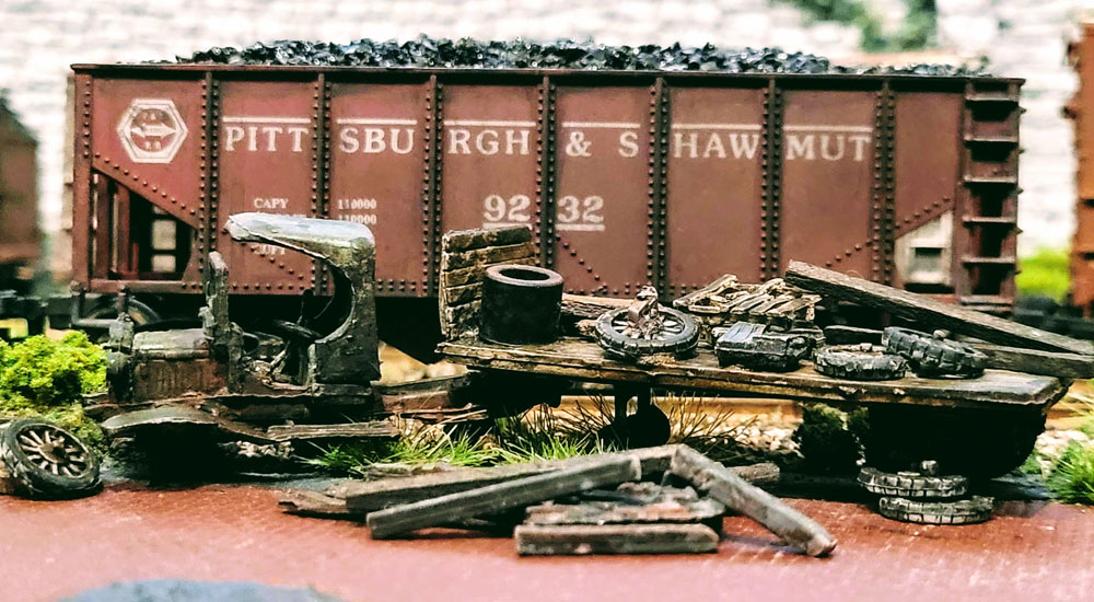 A rusted and broken-down antique truck rests trackside in front of a Pittsburg & Shawmut coal hopper