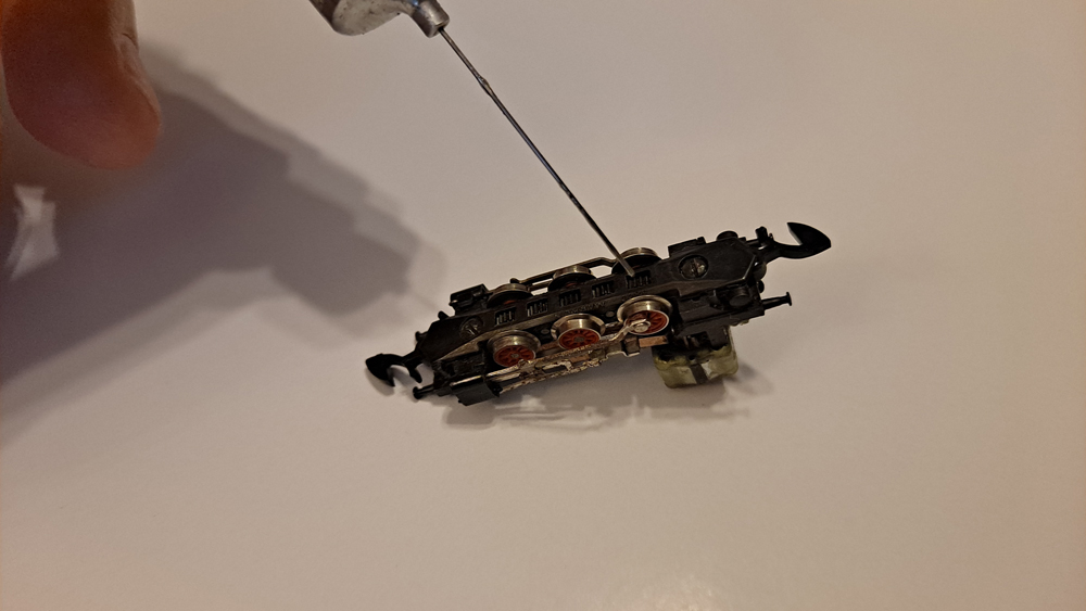 Locomotive upside down showing exposed gears on the drivers.