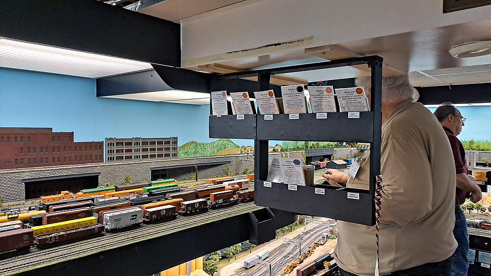 A black frame filled with car cards hangs between two operators.