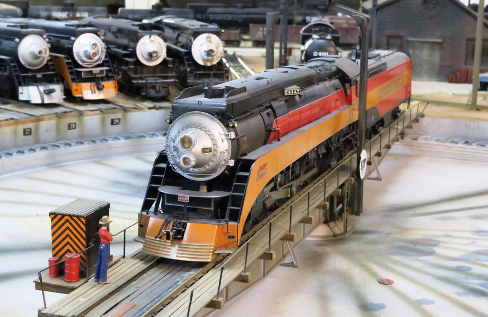 A steam locomotive in the Southern Pacific’s black, red, and orange “Daylight” scheme rides a turntable
