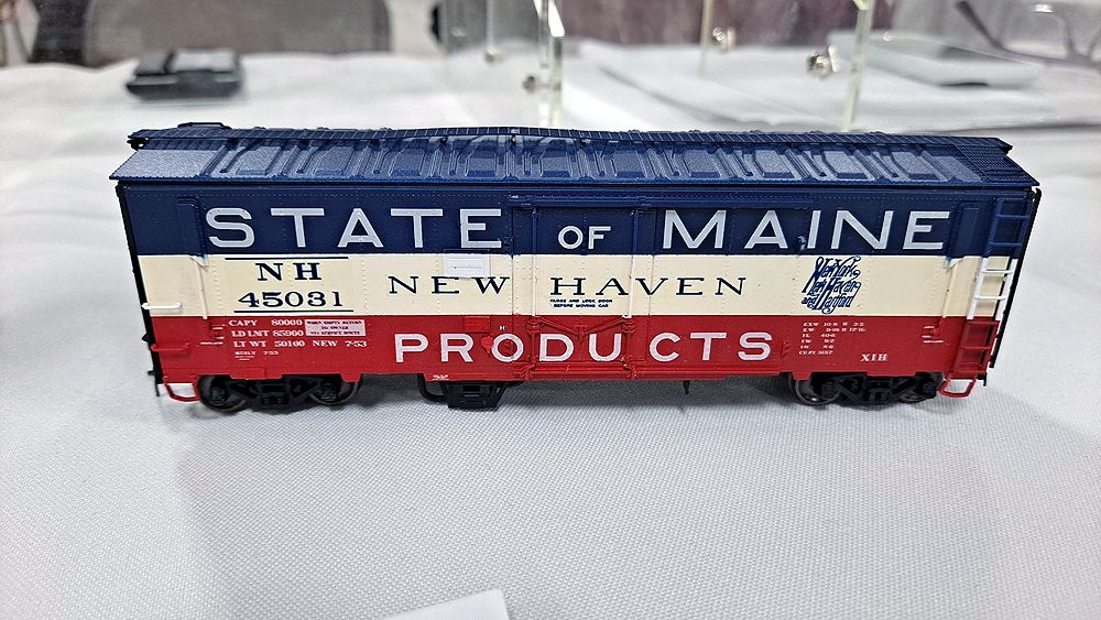 Red, white, and blue State of Maine boxcar with blue roof, white stripe in middle, red stripe at bottom, New Haven lettering in white band.