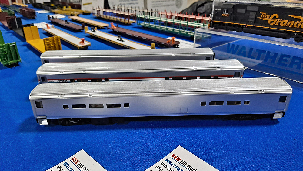 Three silver passenger lounge/café cars on a blue tablecloth.
