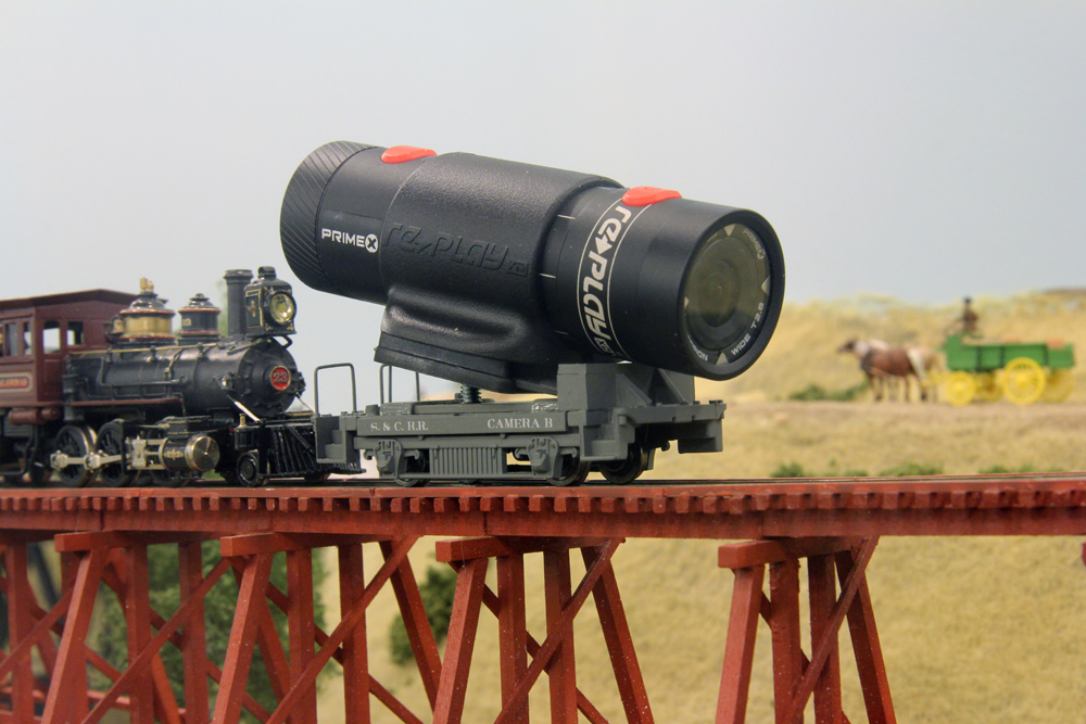 Steam engine pushing caboose underbody with video camera body on top.