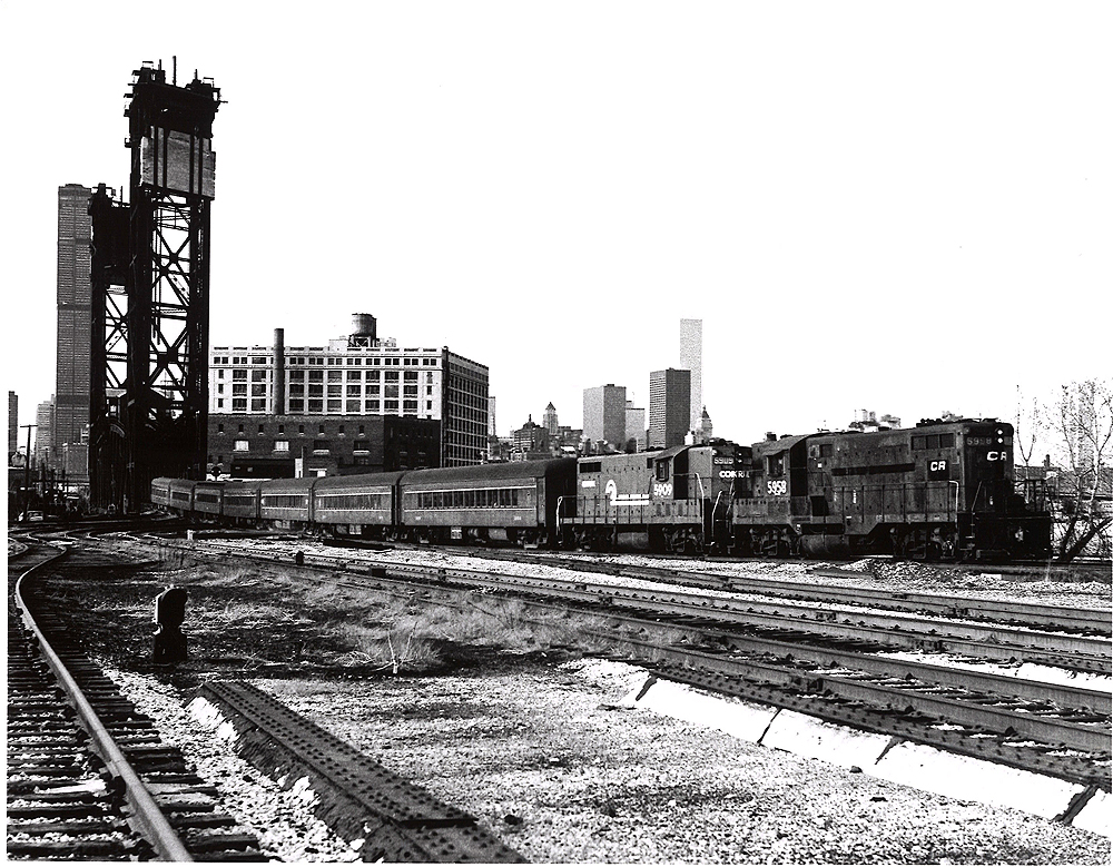 Conrail passenger trains: Two high hood locomotives lead a train through bridge piers.