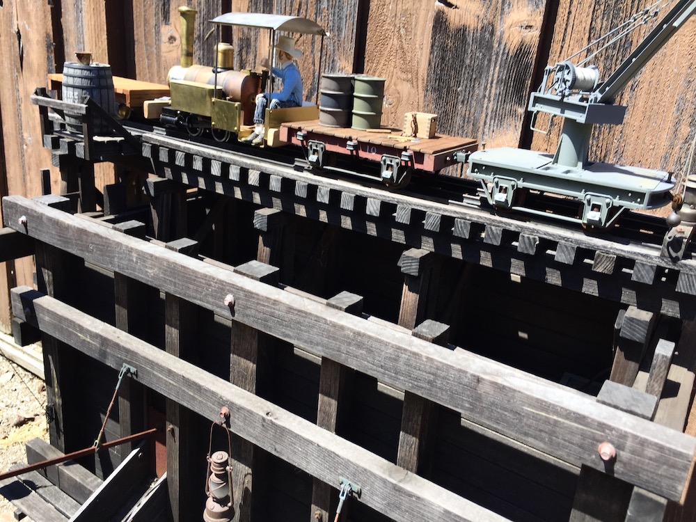 Model locomotive loads ore on a garden railway.