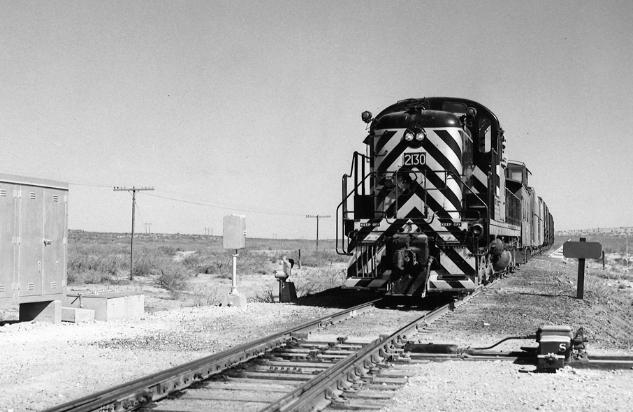 Black and white stripped locomotive paused at a switch.