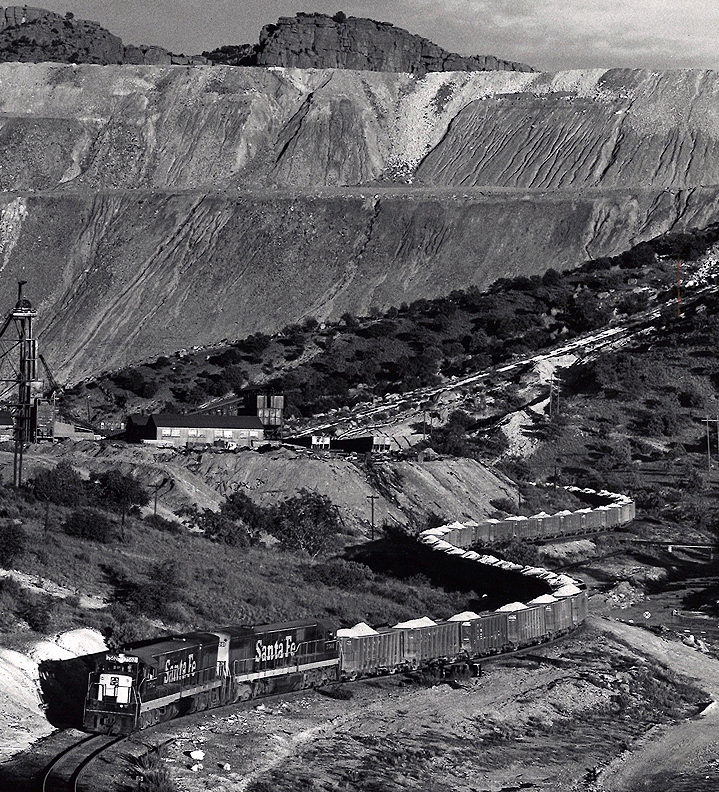 Santa Fe New Mexico branchline train snakes through an arid landscape.