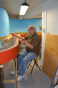Man sitting on chair next to model layout