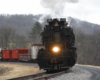 Nose of black steam locomotive and train coming around a bend