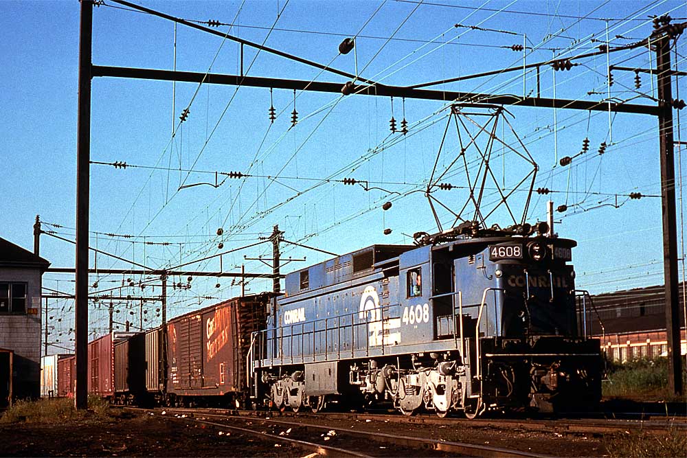 Blue electric locomotive with Conrail freight train under wires