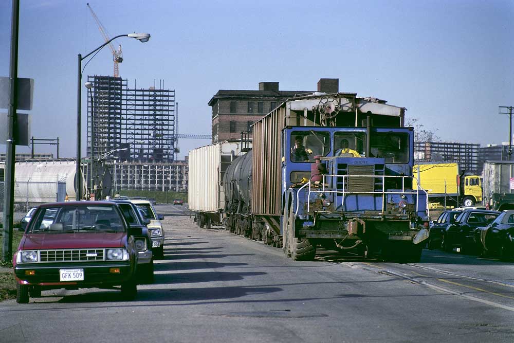 Rubber tired tractor moving rail cars along street trackage