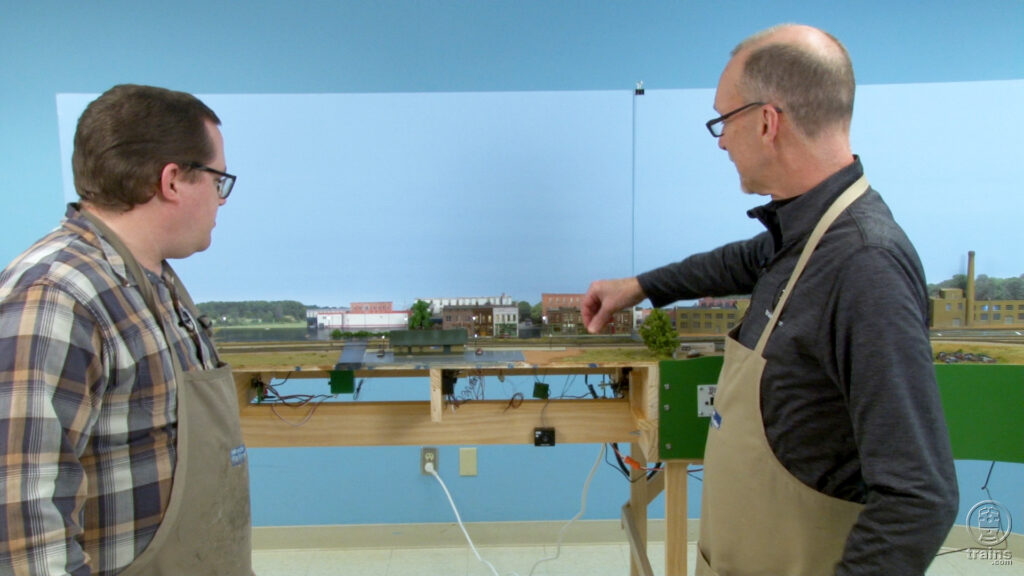 David Popp and Cody Grivno looking at the depot and scenery on a model railroad layout