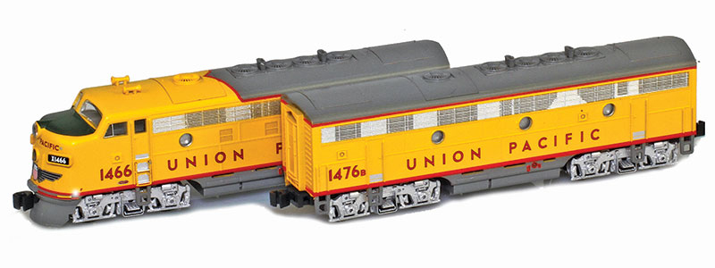 Photo of Z scale Electro-Motive Division F7A and F7B diesel locomotives painted yellow and gray with red graphics and silver trucks on white background.