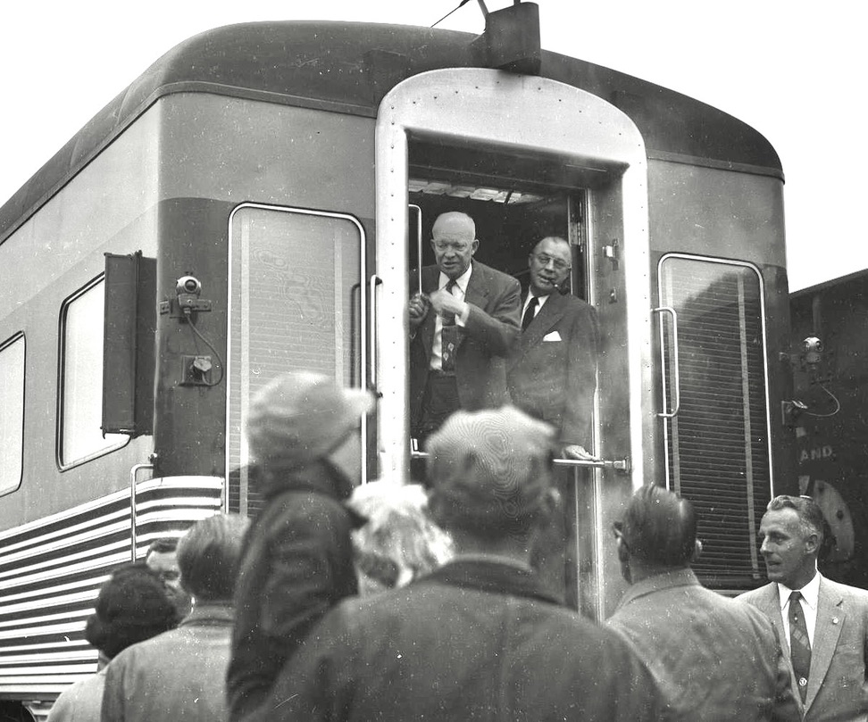 Two men standing in rear doorway of passenger car
