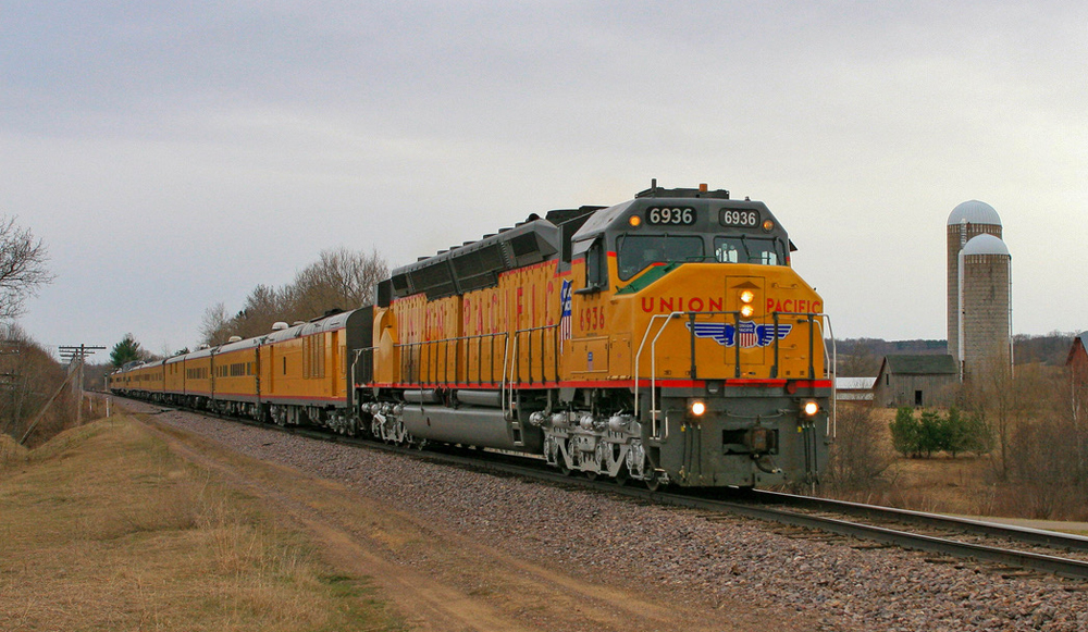 Large yellow diesel locomotive with passenger train