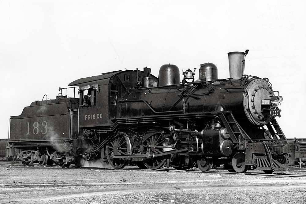 Engineer looks down from cab of steam locomotive with 183 on the tender