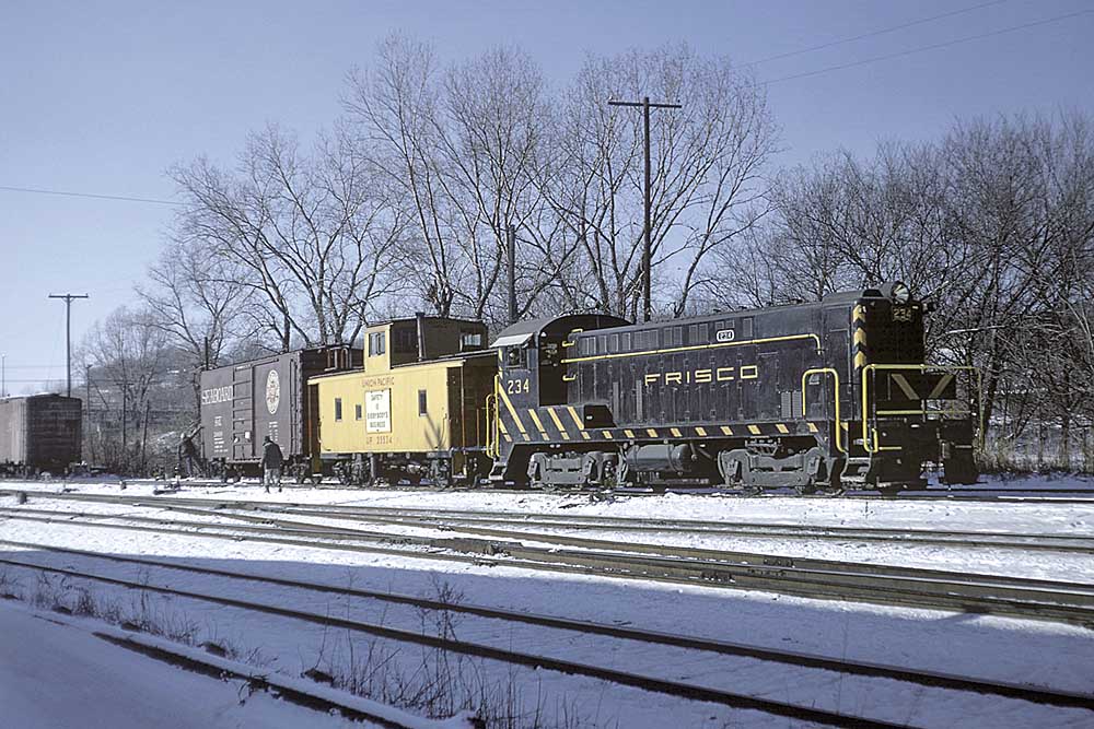 Black and yellow diesel locomotive on freight train with yellow caboose
