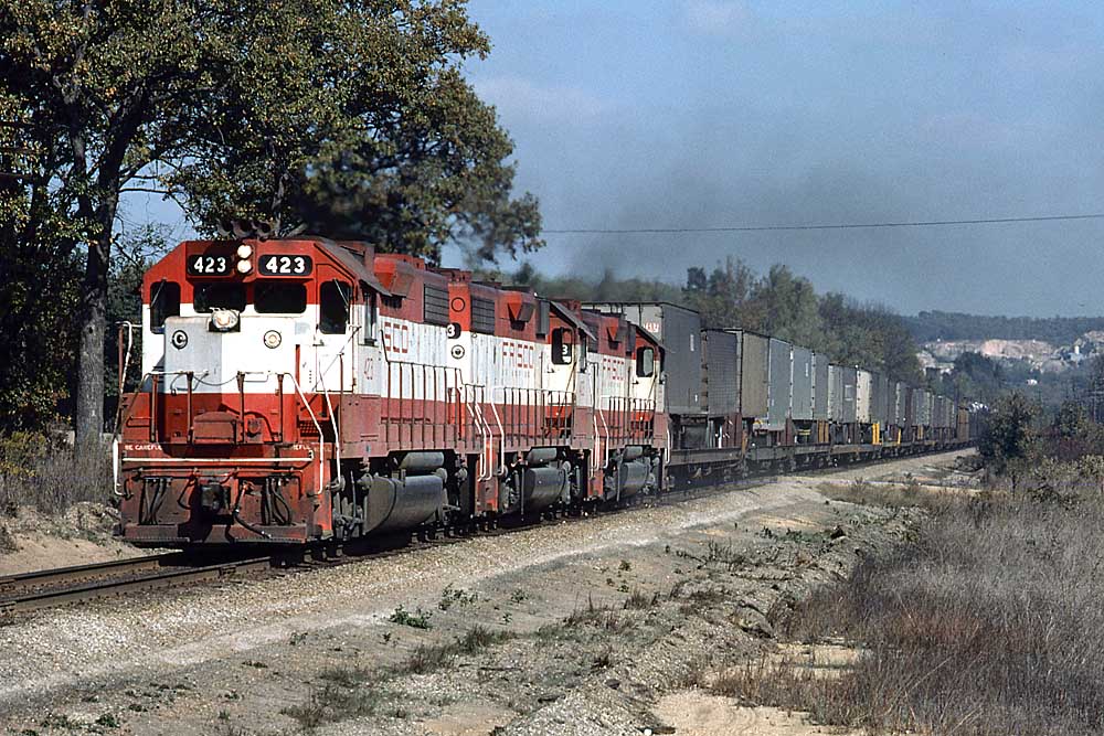 Three red and white diesel locomotives on a Frisco freight train with trailers on flatcars