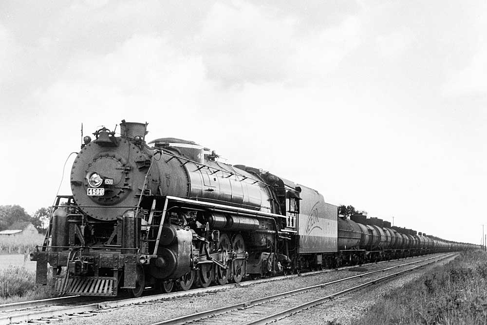 Steam locomotive leads a Frisco freight train with tank cars