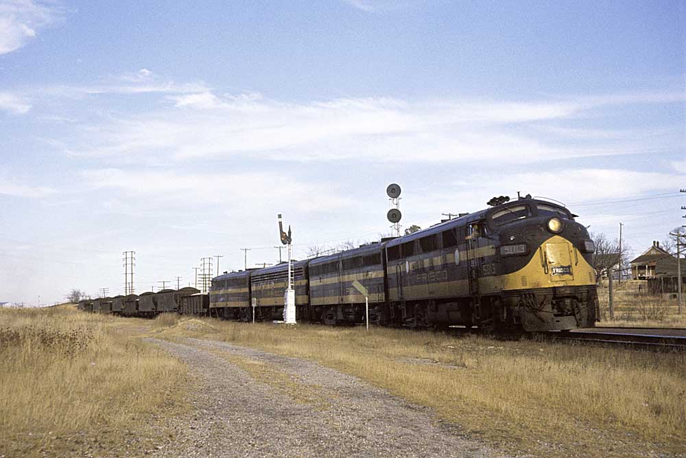 Black and gold diesel locomotives with Frisco freight train between signals