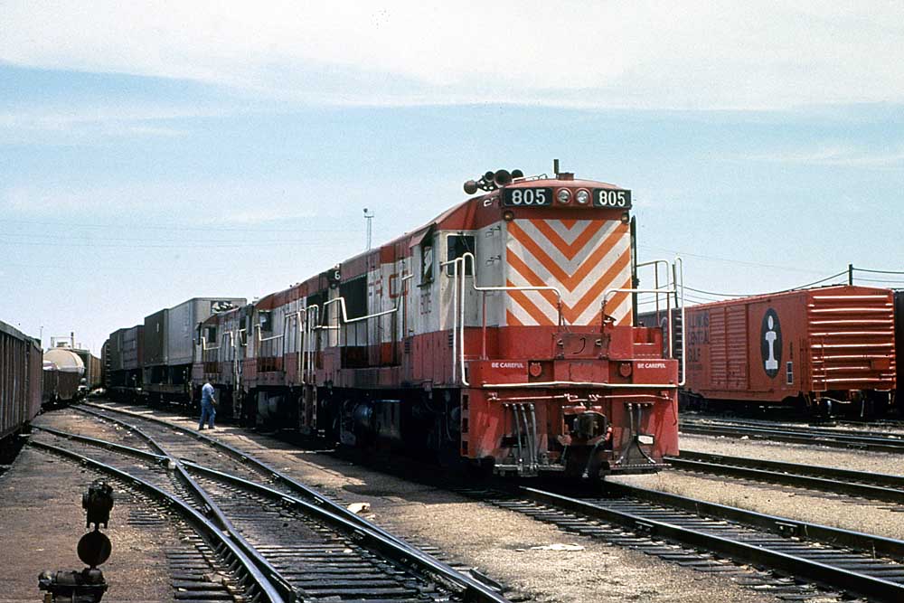 Three red and white diesel locomotives on a Frisco freight train with trailers on flatcars in a yard