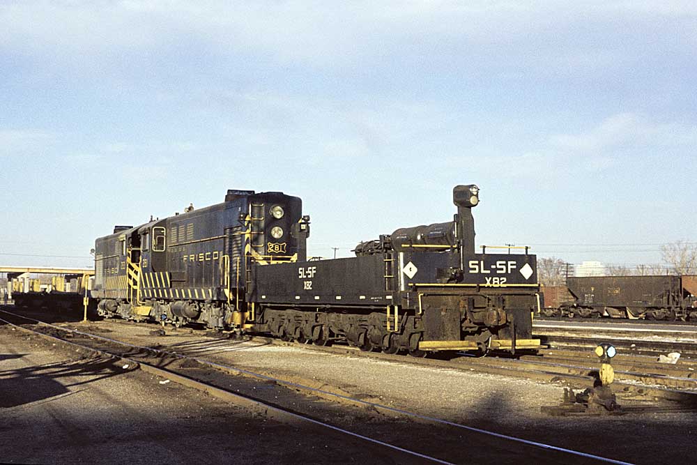Two end-cab diesel locomotive coupled to low-level car with high-mounted headlight