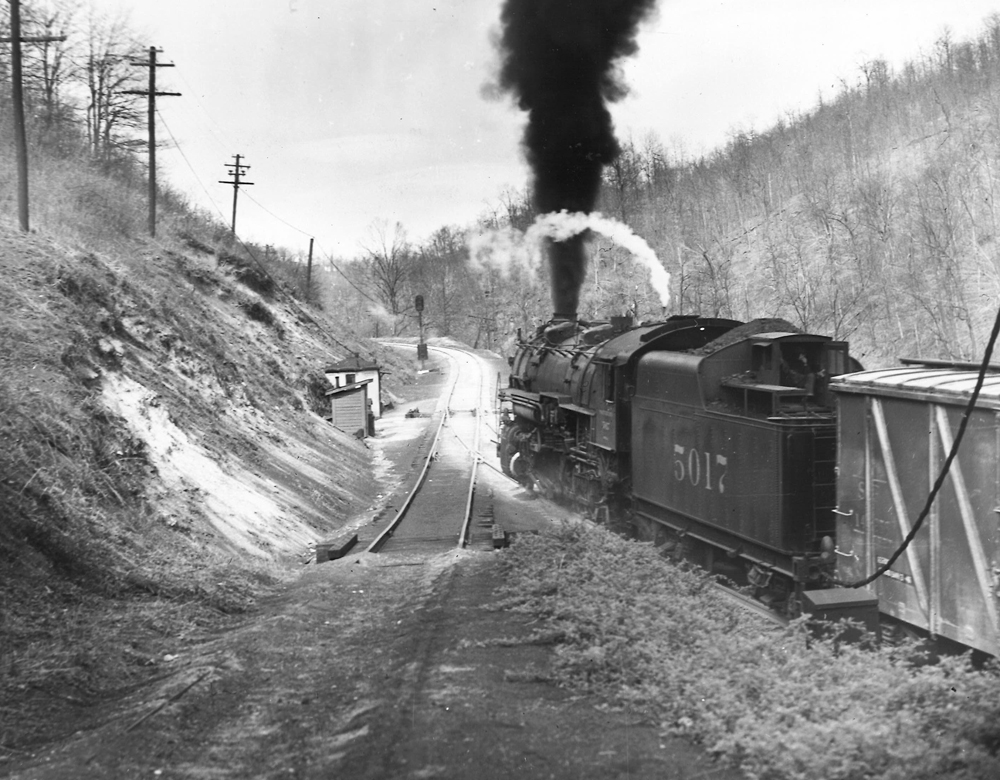 Rear view of a steam locomotive about to climb a steep grade. A runaway ramp is in the foreground.