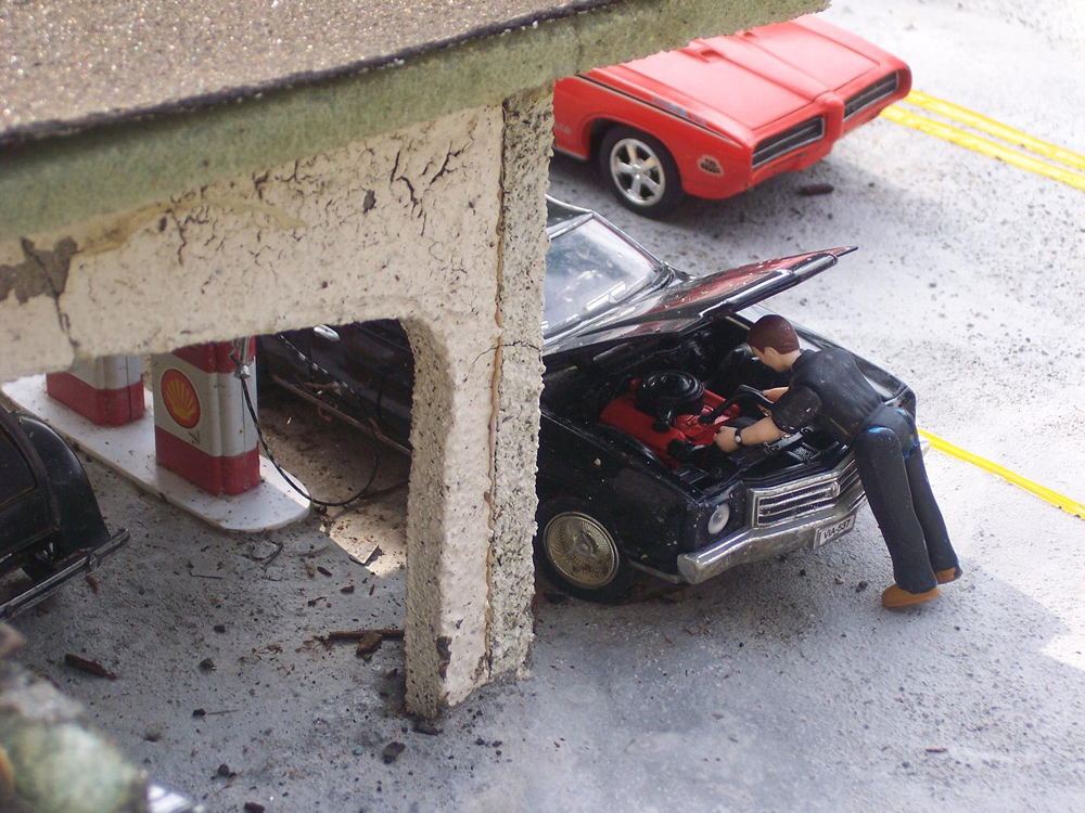 Model figure leans over a model car’s engine
