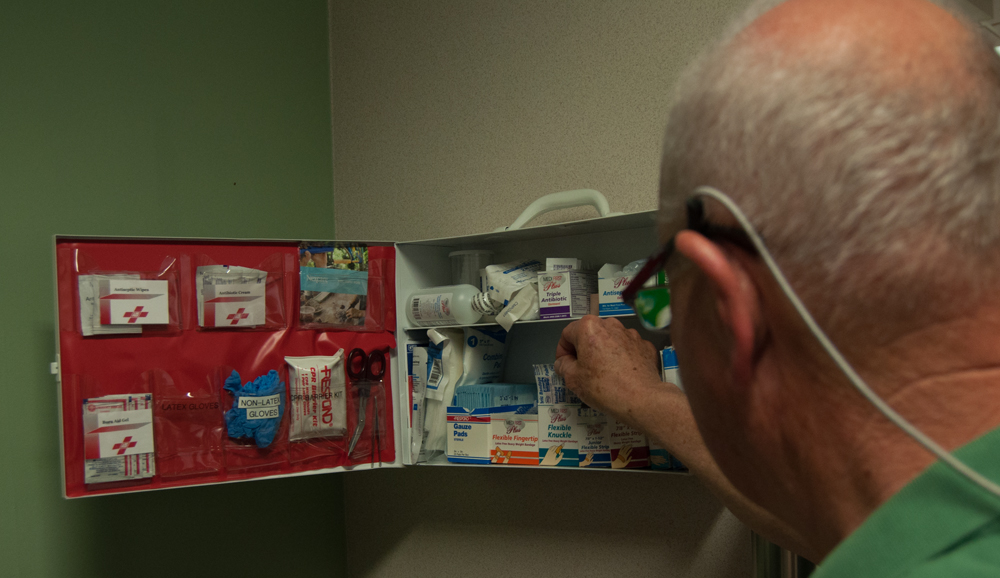 Man with hand raised to first aid kit.