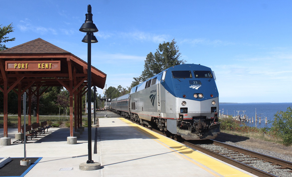 Train stops at open-air station shelter next to lake