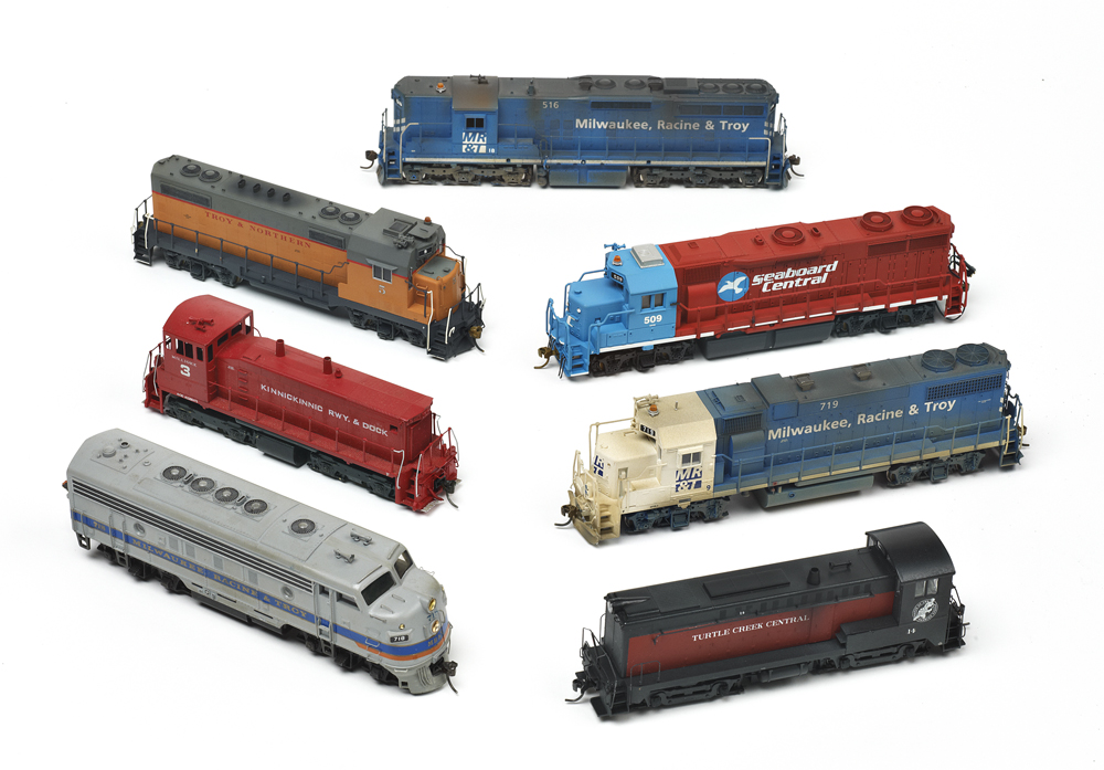 Photo of seven HO scale diesel locomotives on white background.
