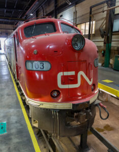 Locomotives with two diesel engines: A red cab unit locomotive in a shop building.