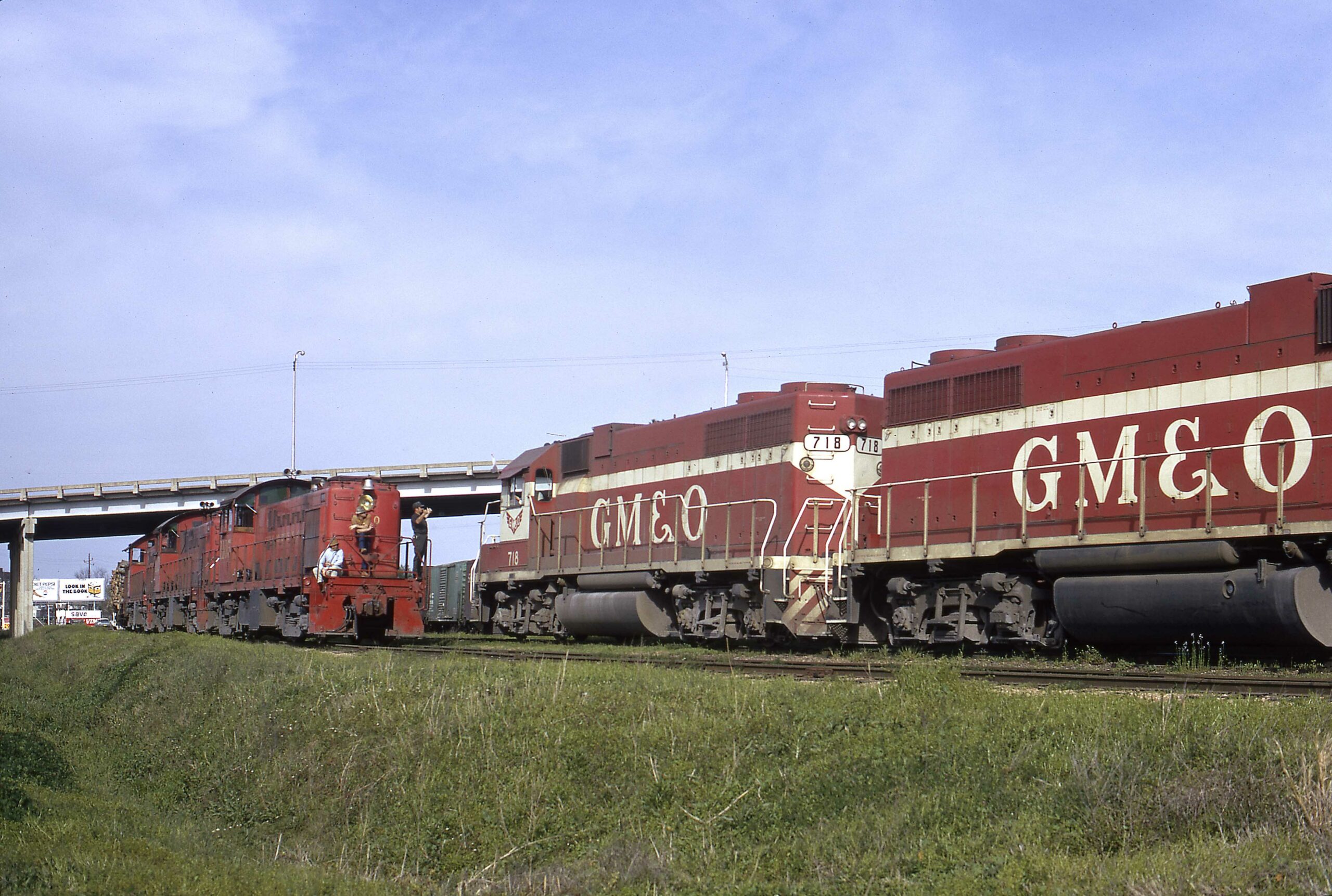 Red and white diesel locomotives meet all-red diesel locomotives under bridge