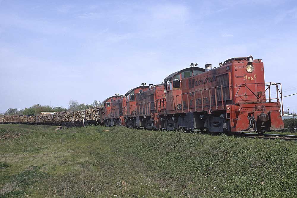 Red diesel locomotives with cars of wood logs
