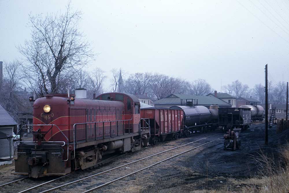 Maroon and red diesel locomotive with freight cars