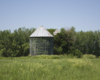 Two metal corn cribs with trees in background