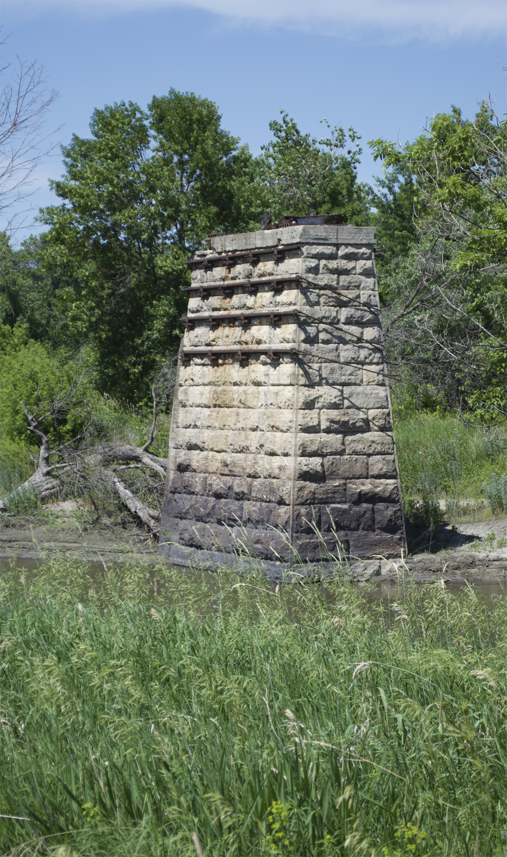 Bridge pier with grass in foreground and trees in background