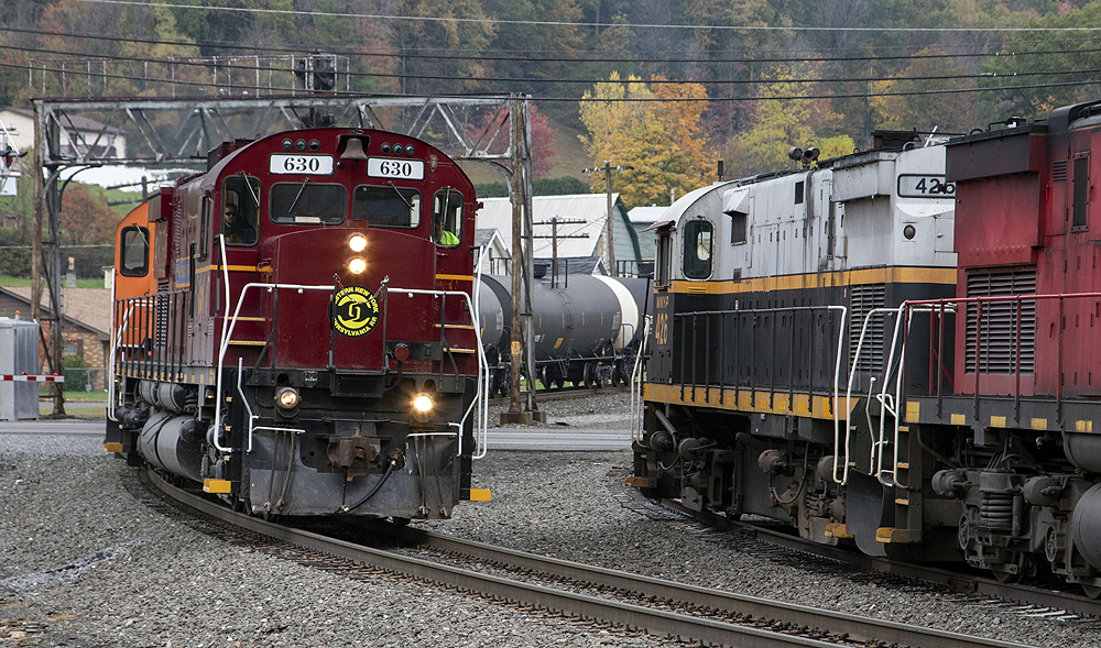 Two trains pass each other on a curve with autumn foliage in the background.