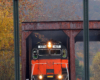 Red-and-black locomotive pictured through a near foreground sign post.