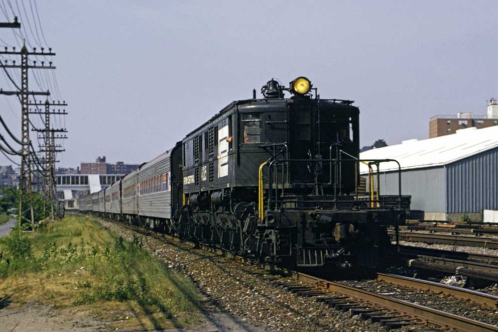 Black and white electric locomotive with passenger train on curve