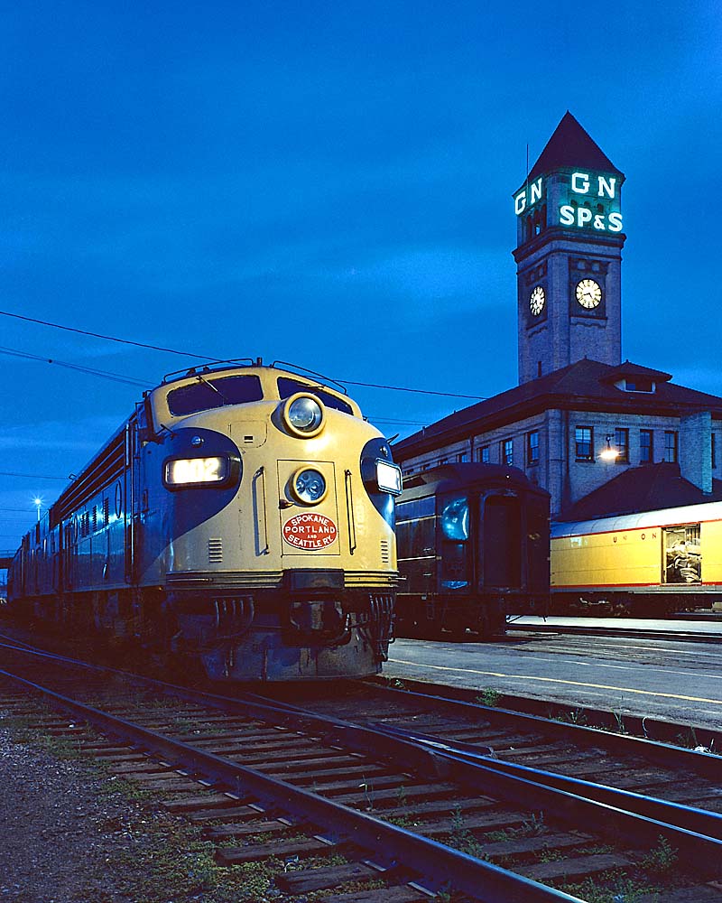 Streamlined diesel locomotive by station with clock tower at twilight