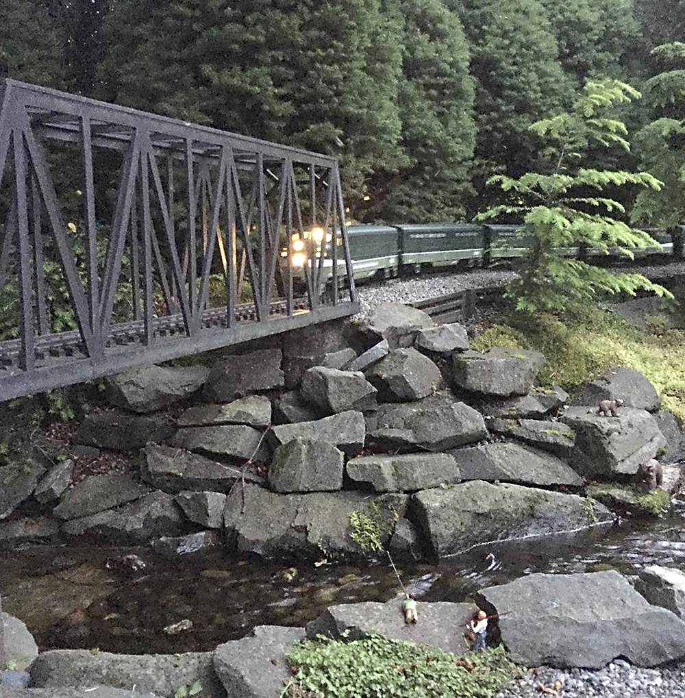 model train crosses bridge over river