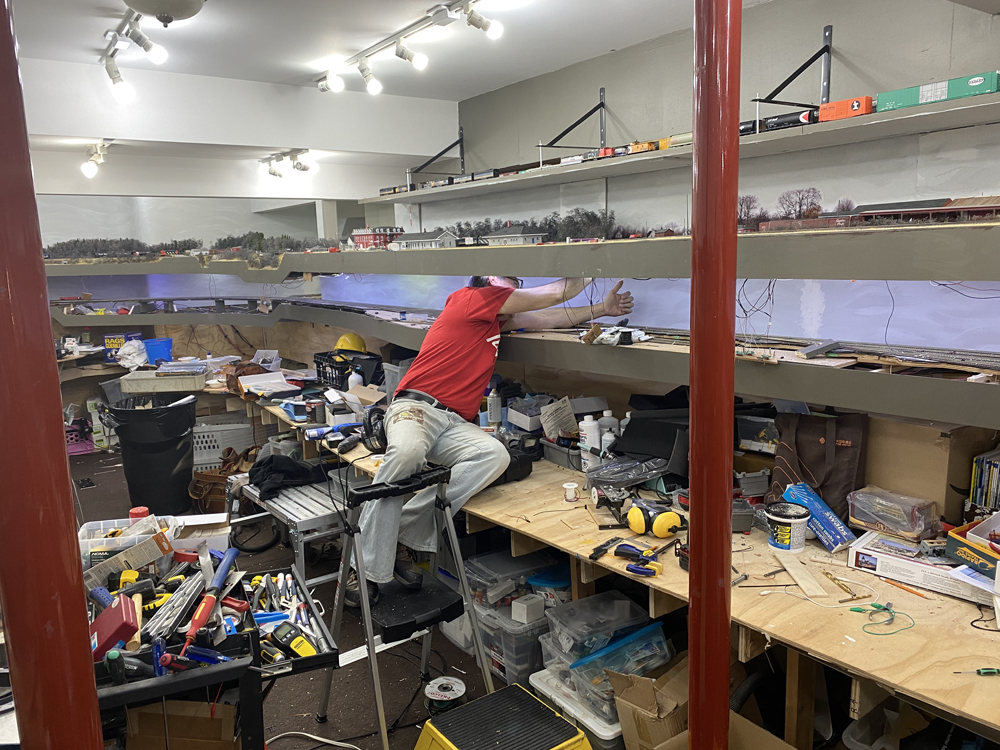 man struggling to do electrical work on layout