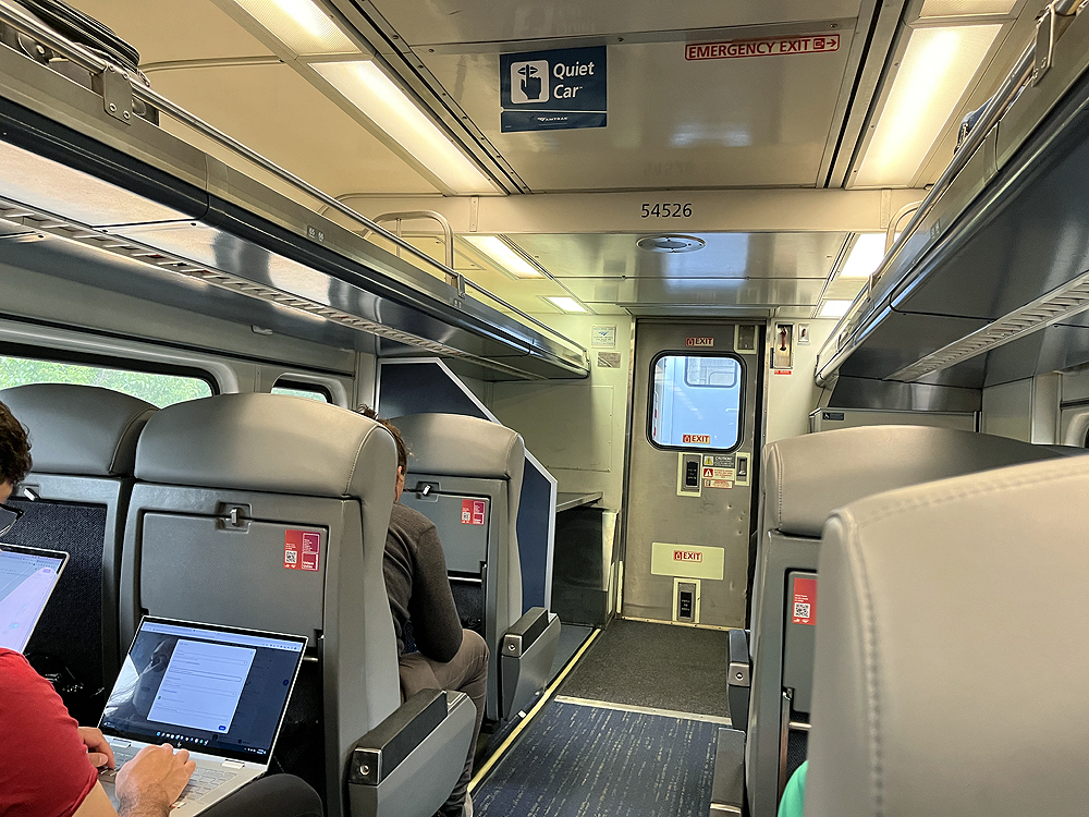 Interior of passenger car with passengers riding train.